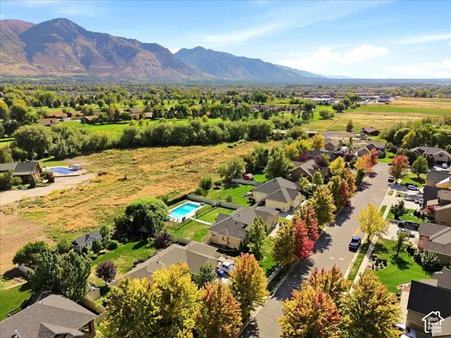 Mountain range backdrop, residential neighborhood setting, mature trees with autumn foliage, paved street, and landscaped yards