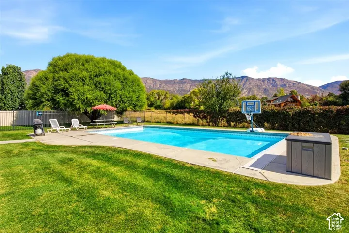 Expansive lawn with a rectangular swimming pool, concrete pool deck, and perimeter fencing
