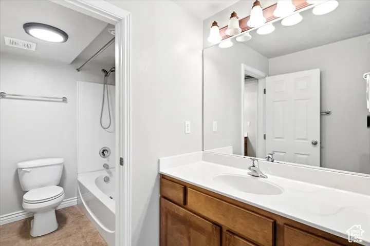 Vanity with wood-finish cabinetry, white countertop, and integrated sink