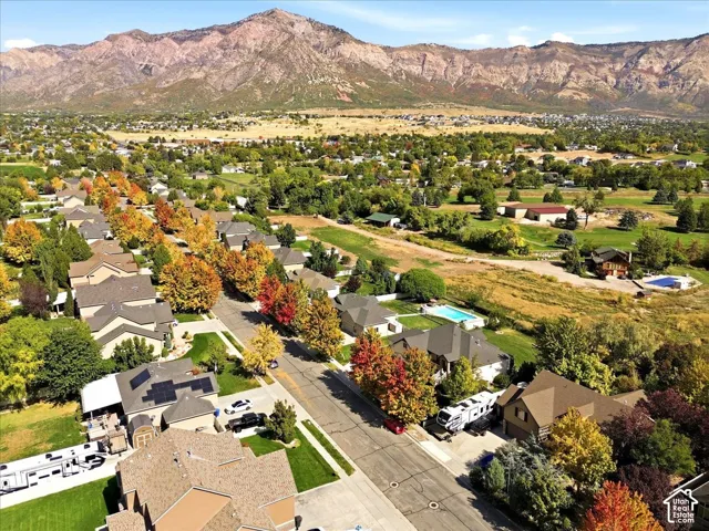 Residential neighborhood with mature trees, mountain backdrop, and multiple properties featuring swimming pools