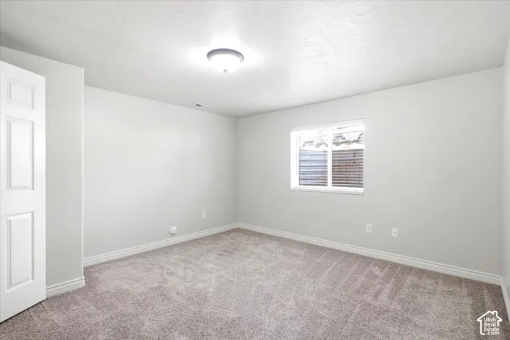 Spacious bedroom featuring neutral wall finishes, neutral carpet flooring, and abundant natural light from dual windows with horizontal blinds