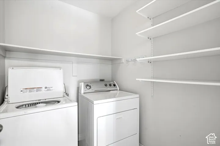 Laundry area featuring a top-load washing machine, front-load dryer, and wall-mounted shelving