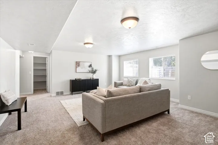 Carpeted living space with multiple windows, recessed lighting, and a built-in storage closet with shelving