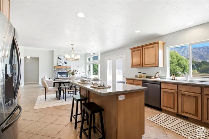 Kitchen featuring a light-toned wood cabinetry, stainless steel appliances, a center island with a light countertop, and tile flooring