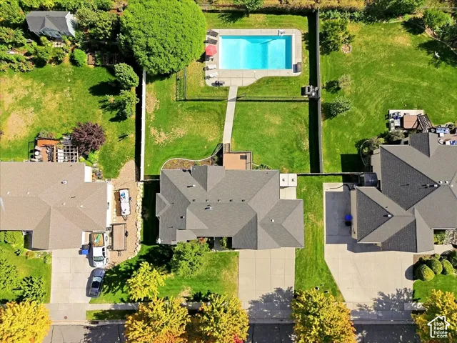 Fenced backyard with an in-ground swimming pool, concrete pool deck, and adjacent green space