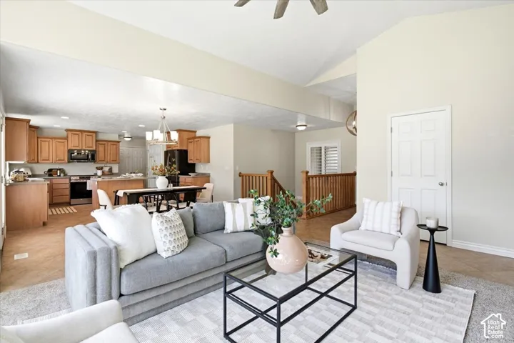 Vaulted ceilings, wood-finish flooring, kitchen with natural wood cabinetry and black appliances, open concept layout, and a staircase with wood railings