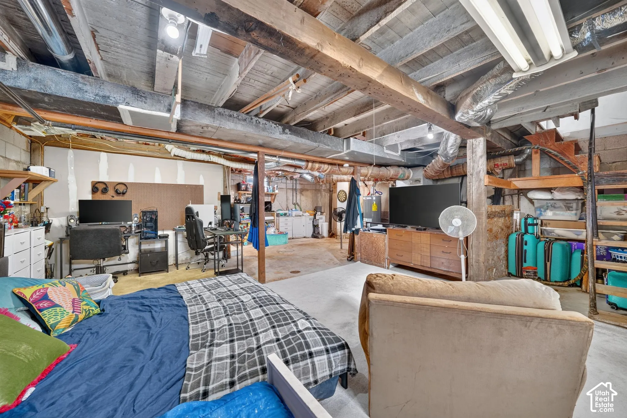 Exposed wood beam ceiling, concrete block wall construction, built-in shelving, concrete flooring, and exposed ductwork