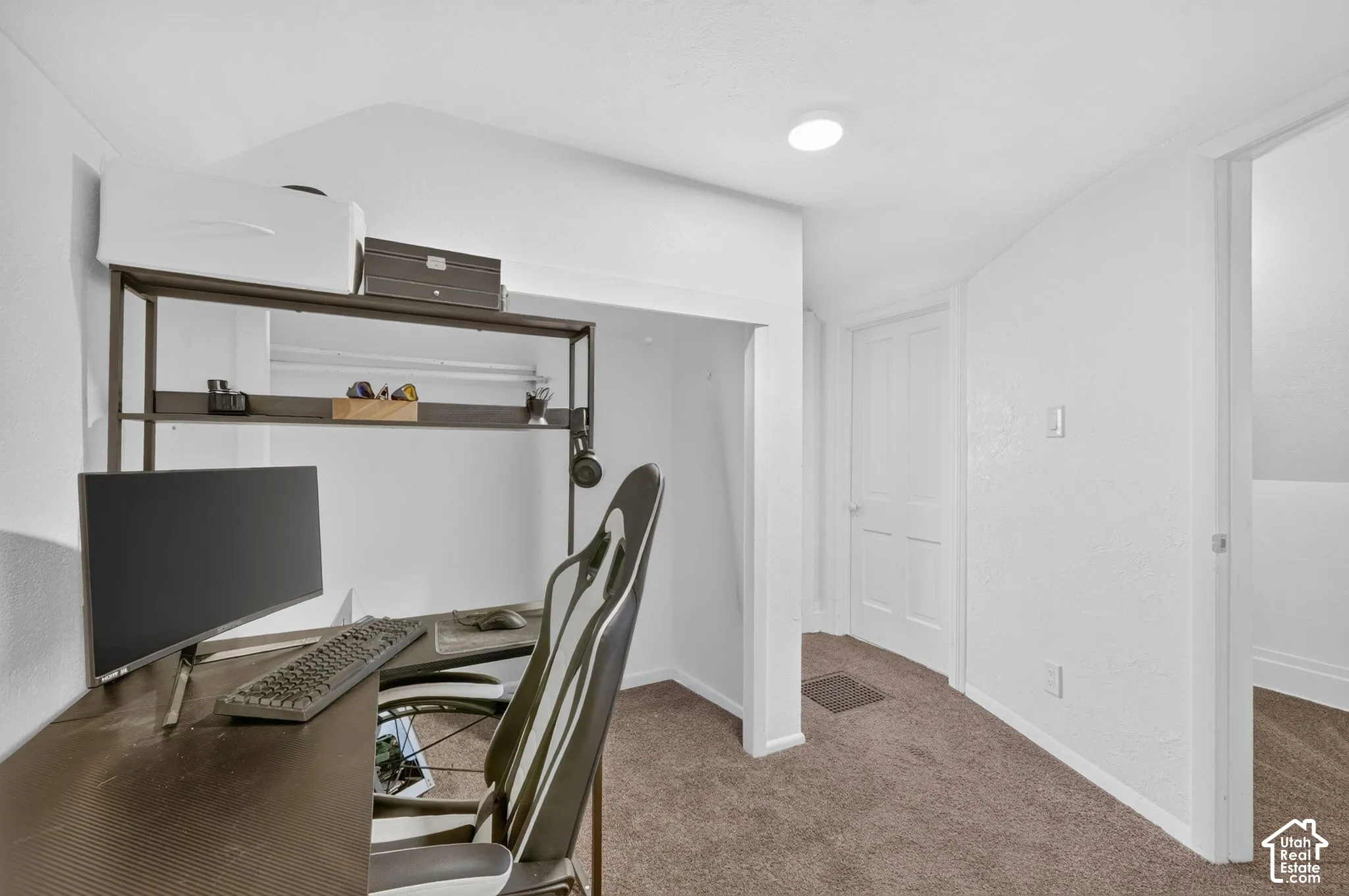 Built-in desk area with shelving, recessed lighting, and neutral carpeting