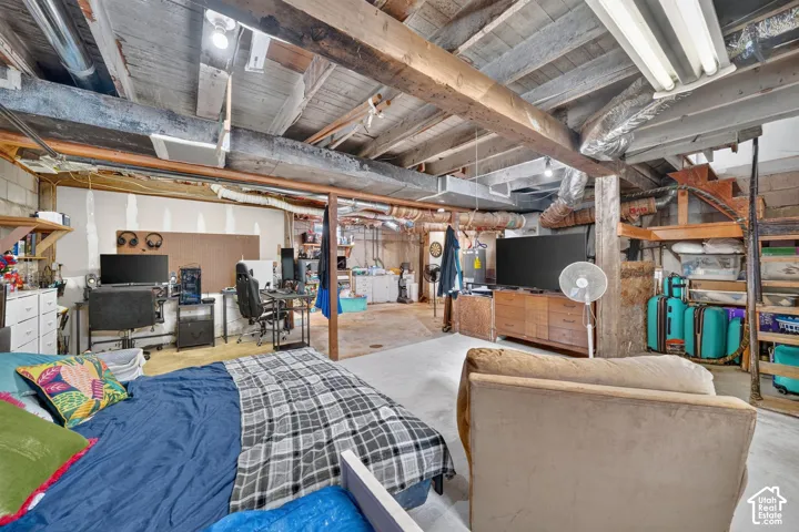 Exposed wood beam ceiling, concrete block wall construction, built-in shelving, concrete flooring, and exposed ductwork