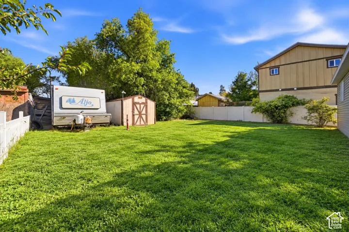 Expansive green lawn with a wood shed, a white picket fence, and a privacy fence