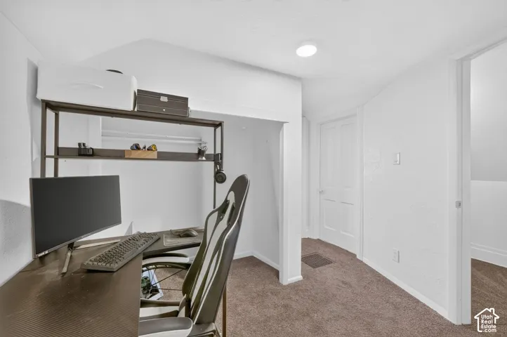 Built-in desk area with shelving, recessed lighting, and neutral carpeting