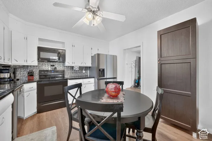 Kitchen featuring white cabinetry, wood-finish flooring, a stainless steel refrigerator, a dark wood pantry, and a decorative backsplash