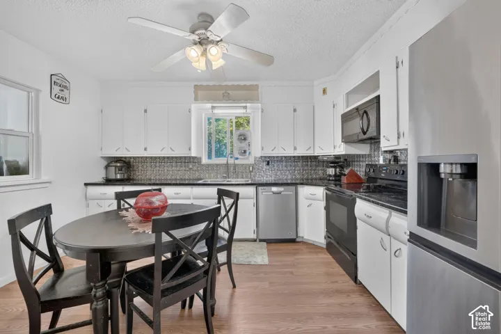 White cabinetry, dark countertops, tile backsplash, and stainless steel appliances