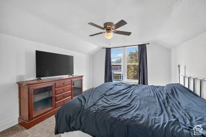 White walls with a textured ceiling, a ceiling fan with integrated lighting, and a double window with dark curtains