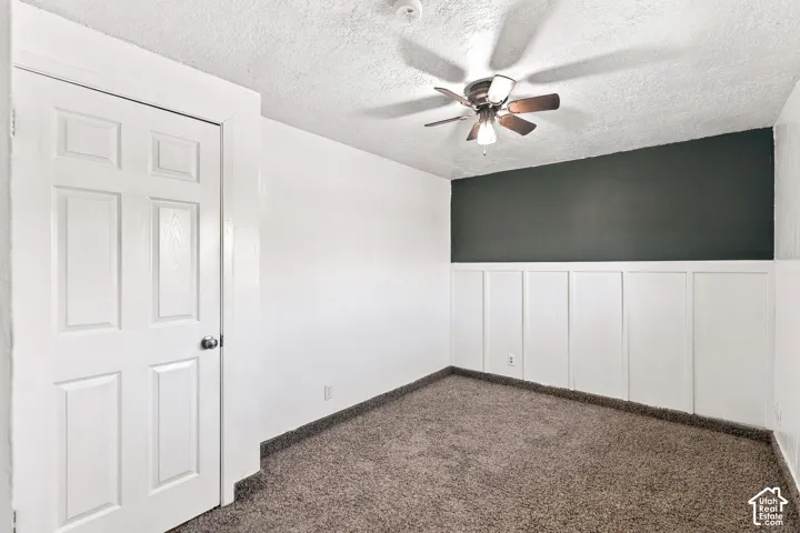 Textured carpeting, two-toned wall with wainscoting, and a ceiling fan