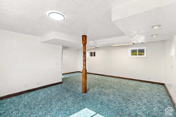 Spacious room featuring light blue patterned carpeting, a wood post, and multiple windows