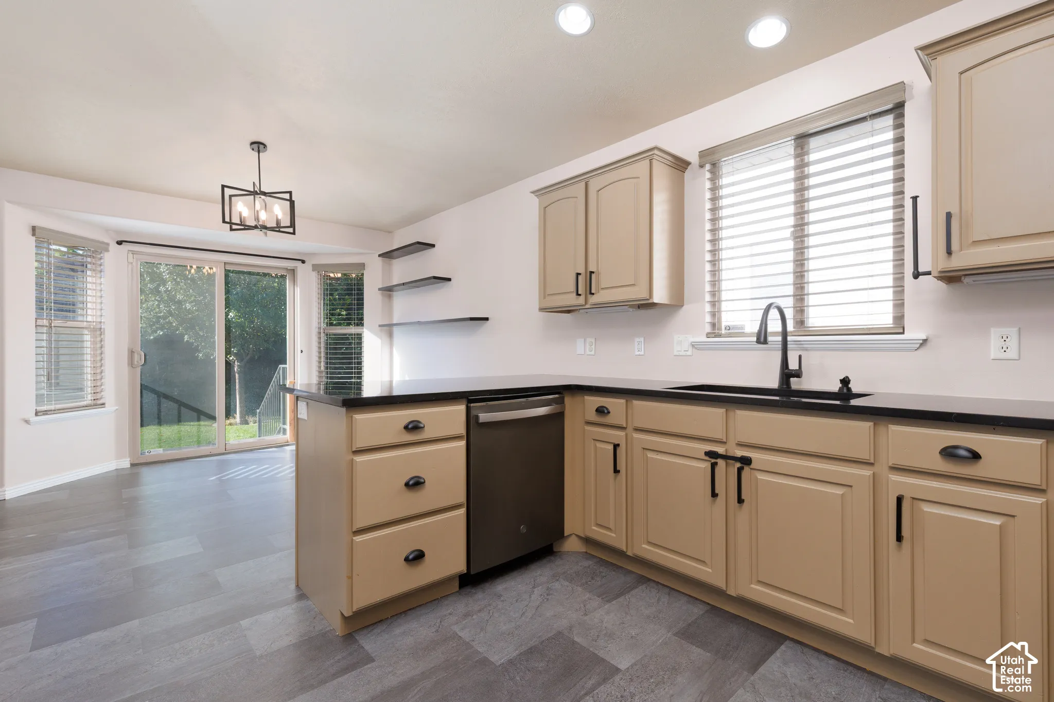 Light-toned cabinetry with dark hardware, black countertops, and a stainless steel dishwasher