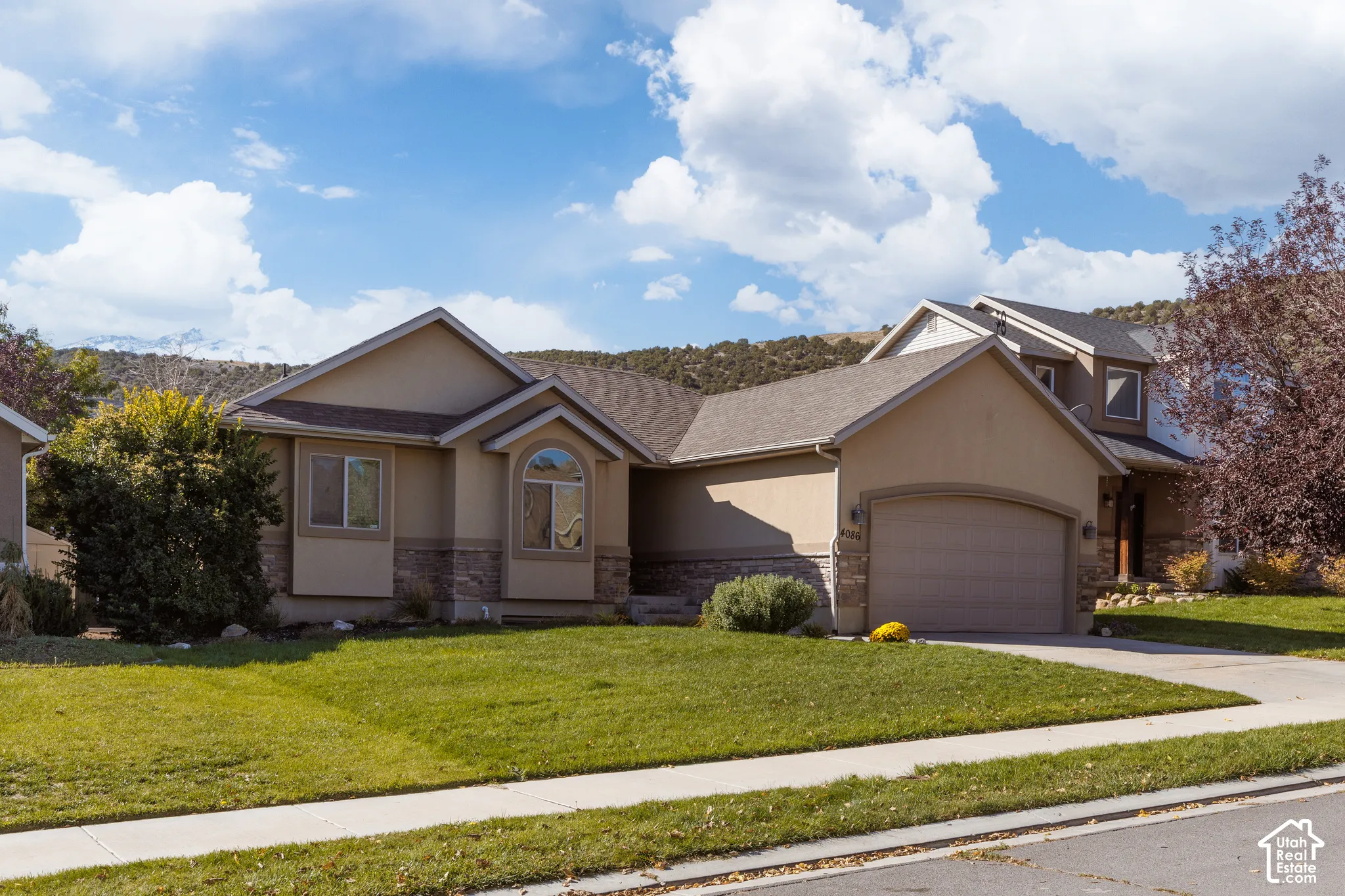 Stucco exterior with stone accents, arched garage door, and a prominent arched window