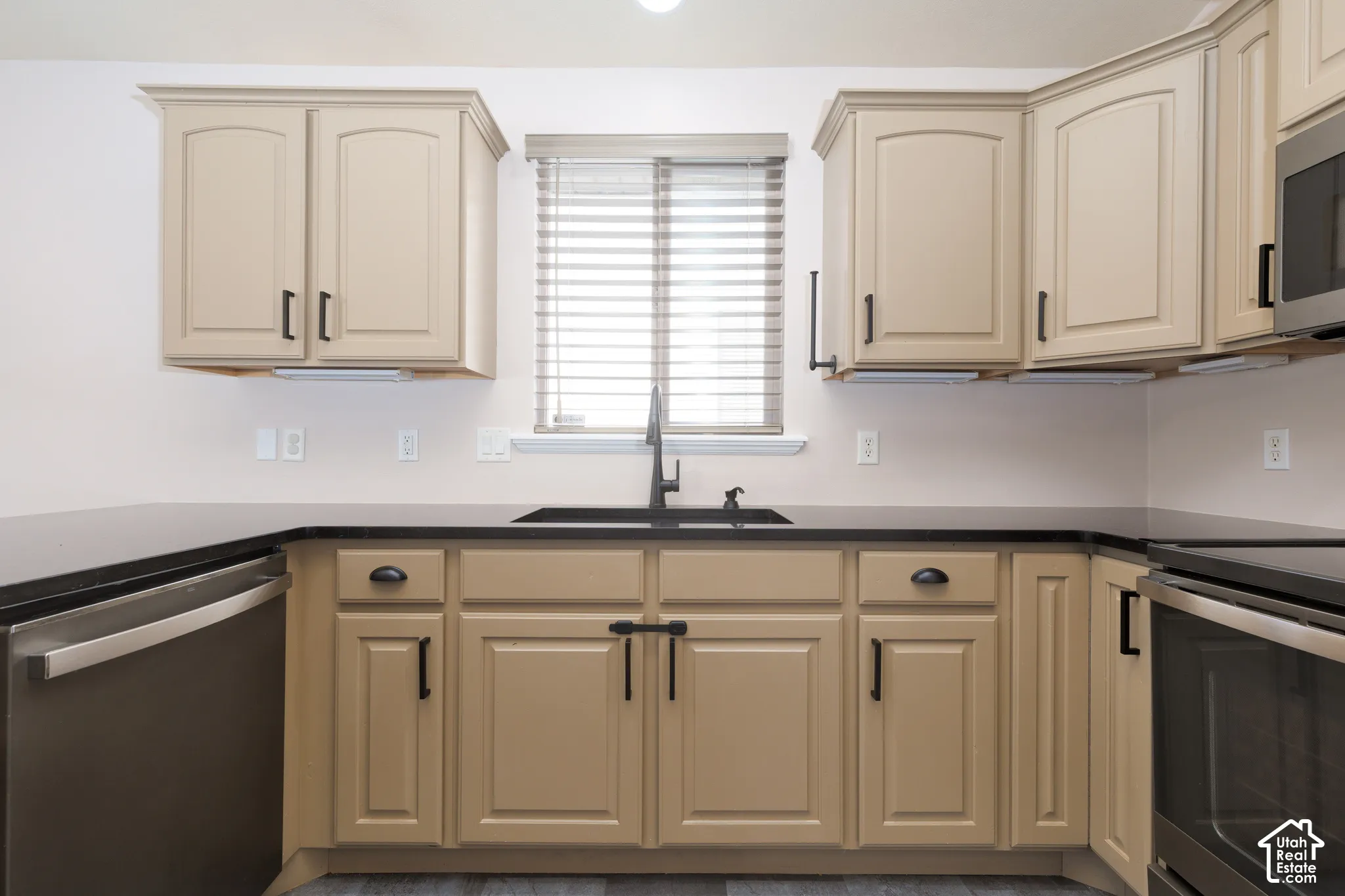 Kitchen featuring wood-finish cabinetry, dark countertops, and a stainless steel dishwasher
