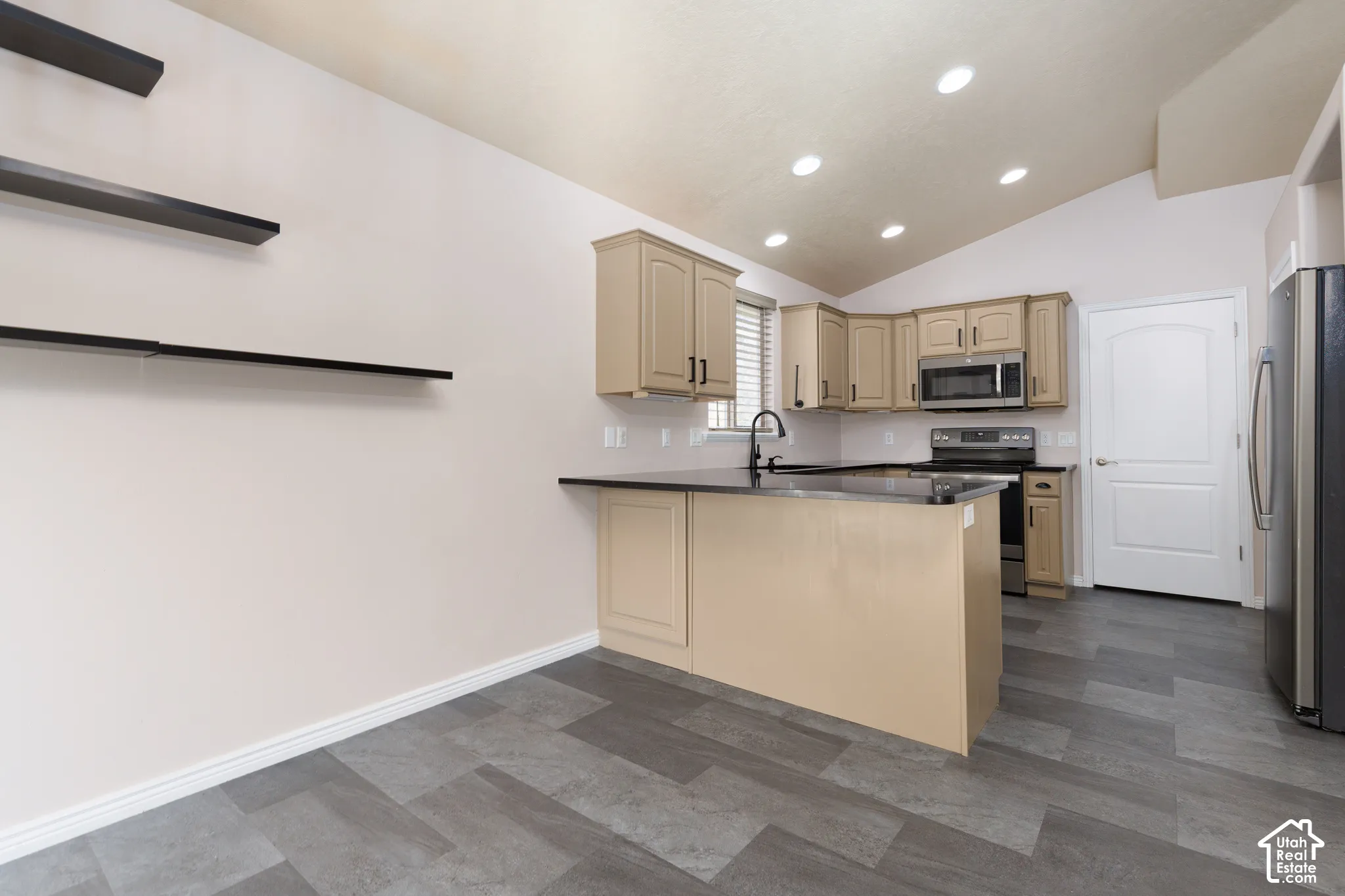 Kitchen featuring a vaulted ceiling, recessed lighting, wood-finish flooring, corner cabinetry, and a central island with a sink