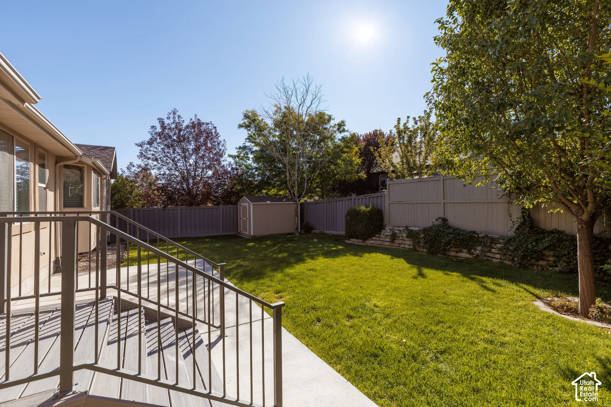 Expansive backyard featuring a manicured lawn, established trees, and a storage shed