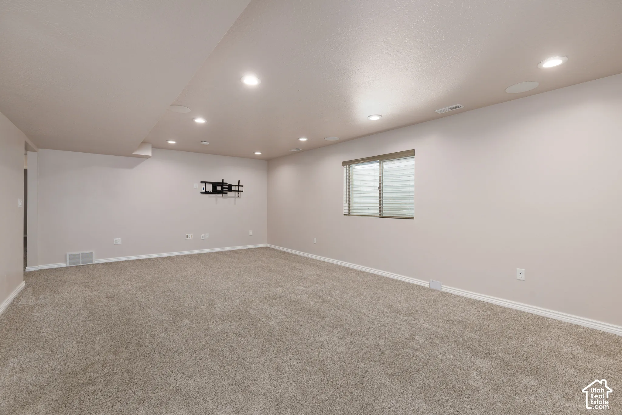 Recessed lighting illuminates the carpeted floor and neutral-toned walls