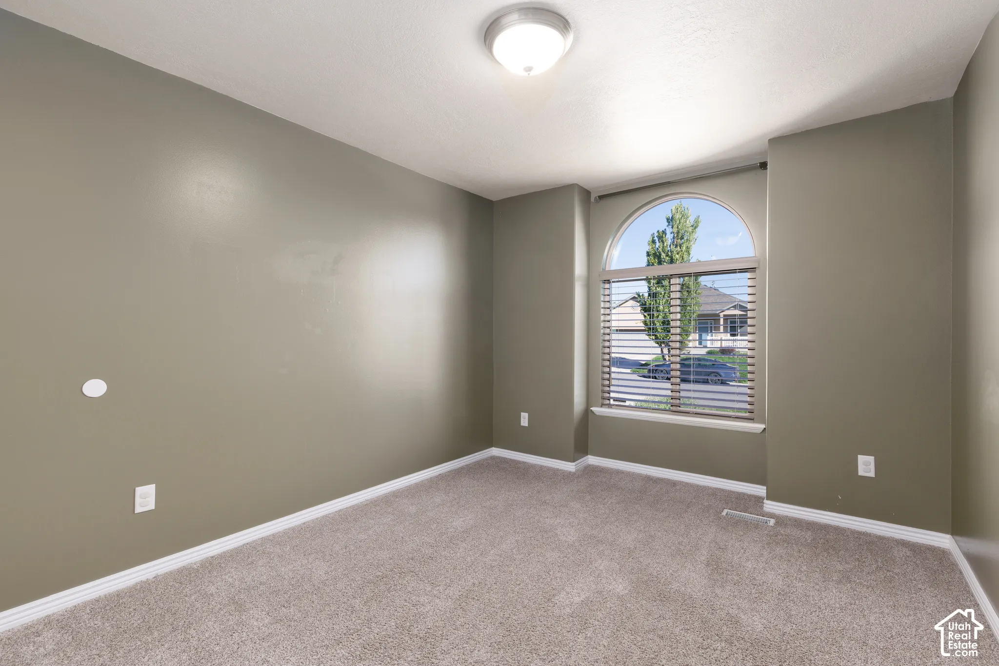 Arched window with blinds, recessed ceiling light, and neutral-toned wall paint