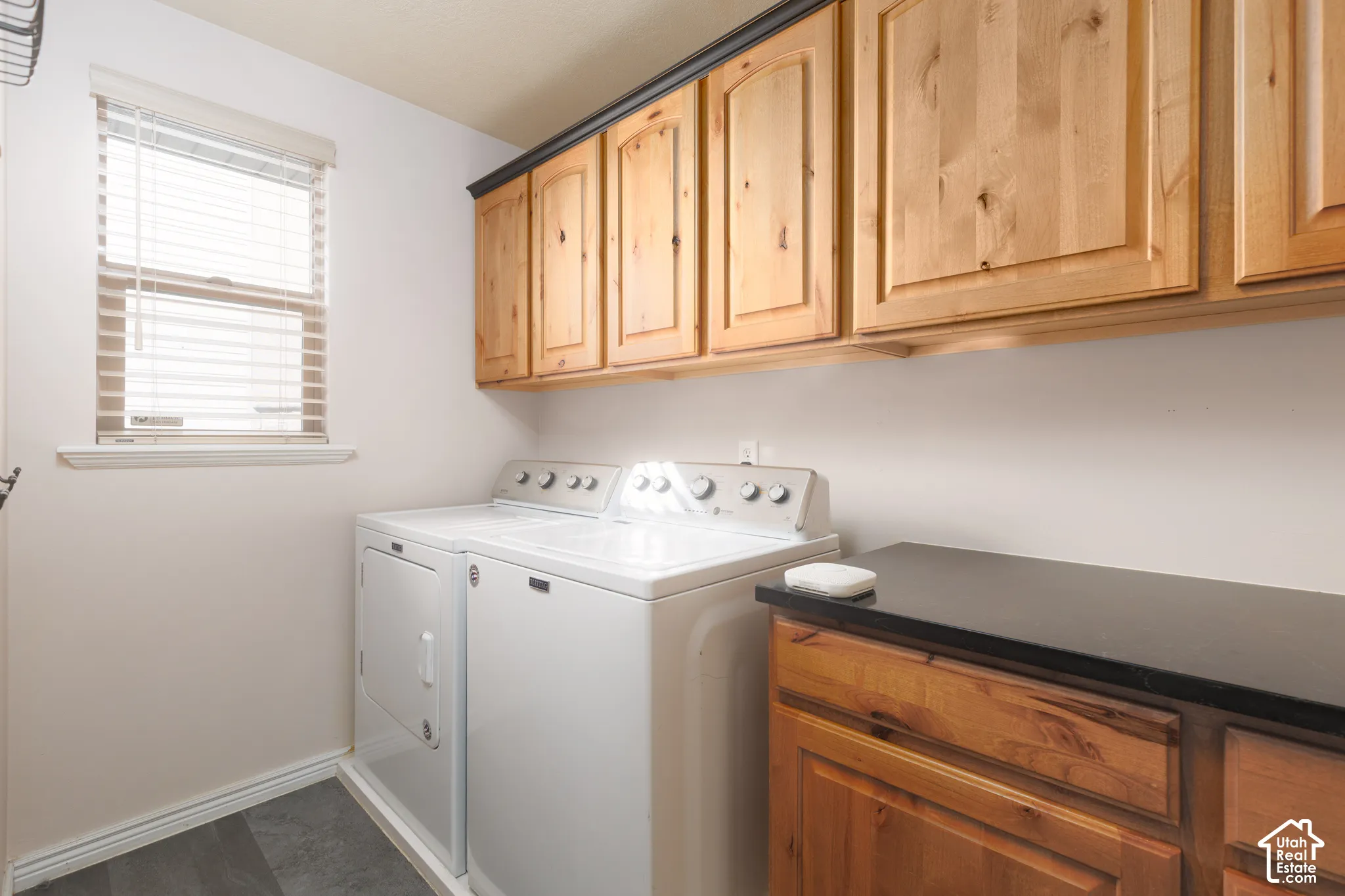 Wood-finish flooring, natural wood cabinetry, and a dark countertop provide functional appeal