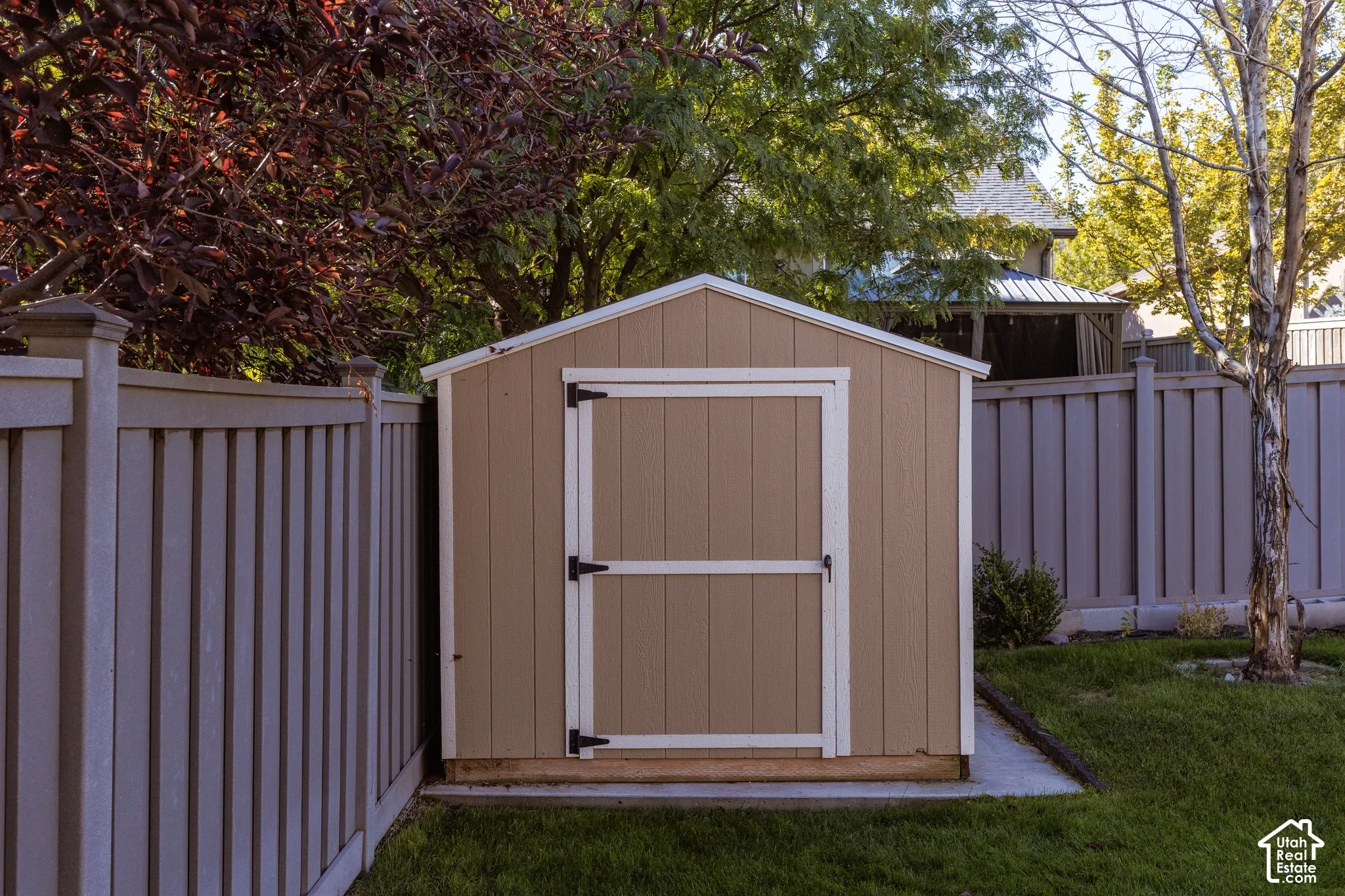 Outdoor storage shed with a gable roof, double doors, and a neutral-toned finish