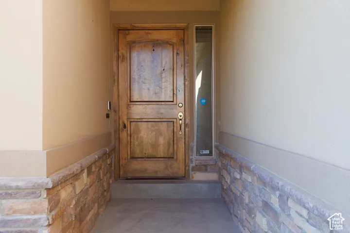Welcoming entry featuring a solid wood two-panel exterior door with hardware detail, flanked by stone veneer wainscoting and neutral wall finishes