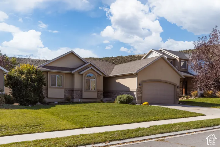 Stucco exterior with stone accents, arched garage door, and a prominent arched window