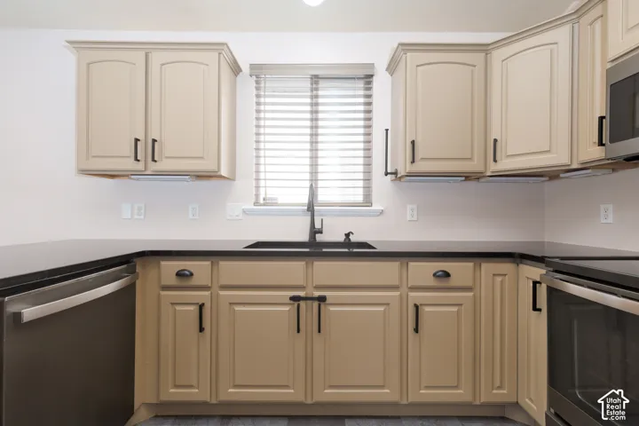 Kitchen featuring wood-finish cabinetry, dark countertops, and a stainless steel dishwasher