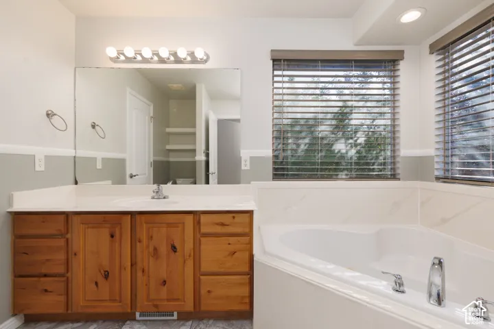 Extended vanity with wood-finish cabinetry, integrated sink, and a large mirror