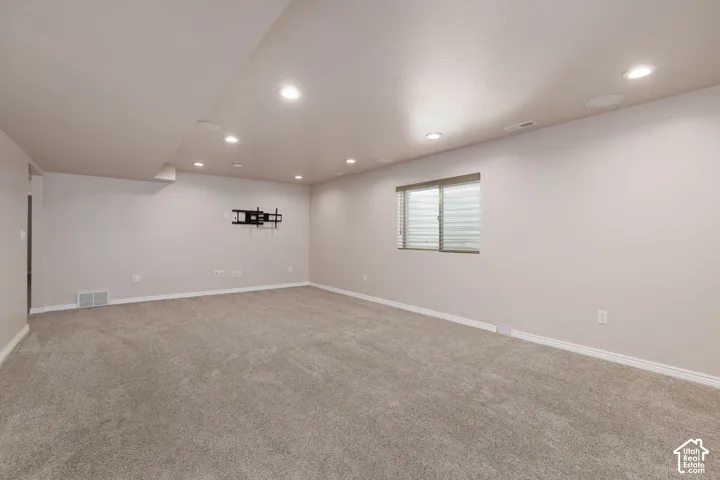 Recessed lighting illuminates the carpeted floor and neutral-toned walls