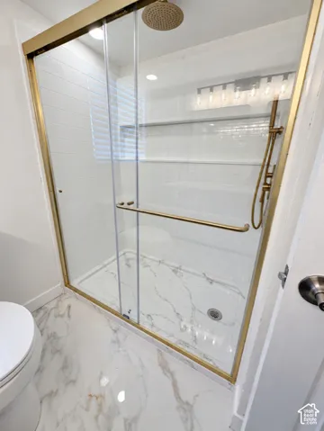 Shower enclosure with a gold-tone frame, sliding glass door, and a rainfall showerhead