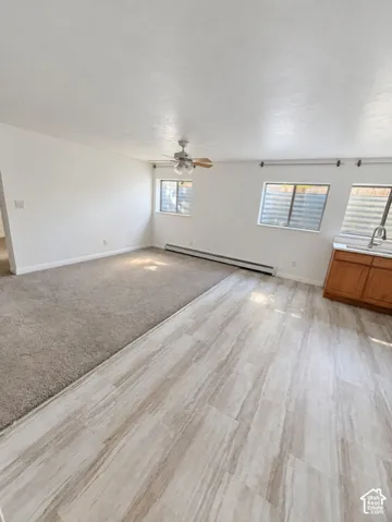 Recessed lighting, wood-finish flooring, wood cabinetry, stainless steel sink with gooseneck faucet, and ceiling fan