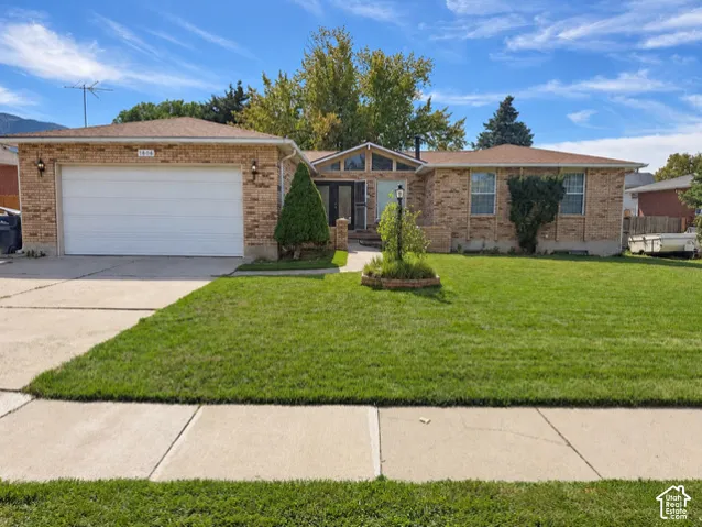 Brick exterior with an attached garage, landscaped front yard, and a concrete driveway