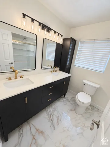 Dual vanity featuring white countertops, undermount sinks, and gold-finish fixtures