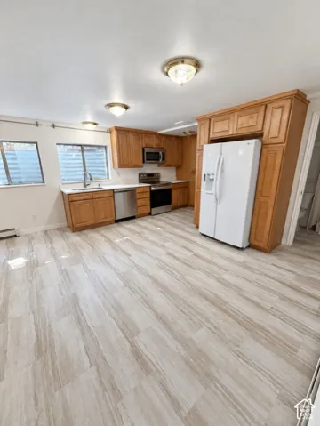 Kitchen featuring wood cabinetry, stainless steel appliances, white countertops, and wood-finish flooring