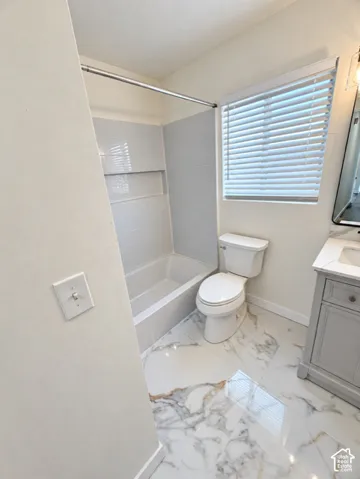 White tiled bathtub with a built-in niche, white toilet, vanity with integrated sink, and patterned floor tile