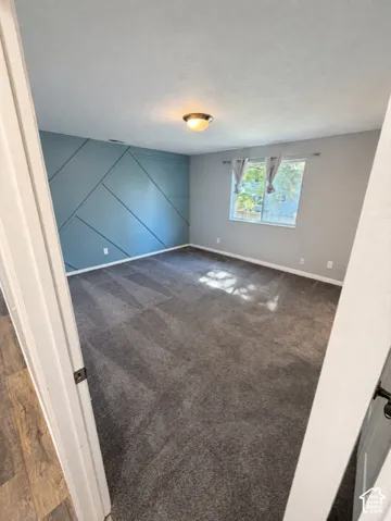 Wall-to-wall carpeting, geometric accent wall, and ceiling-mounted light fixture