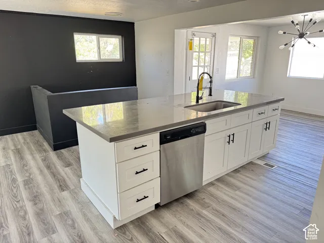 Central island featuring an undermount sink with a gooseneck faucet, light-colored countertop, and white cabinetry with dark hardware