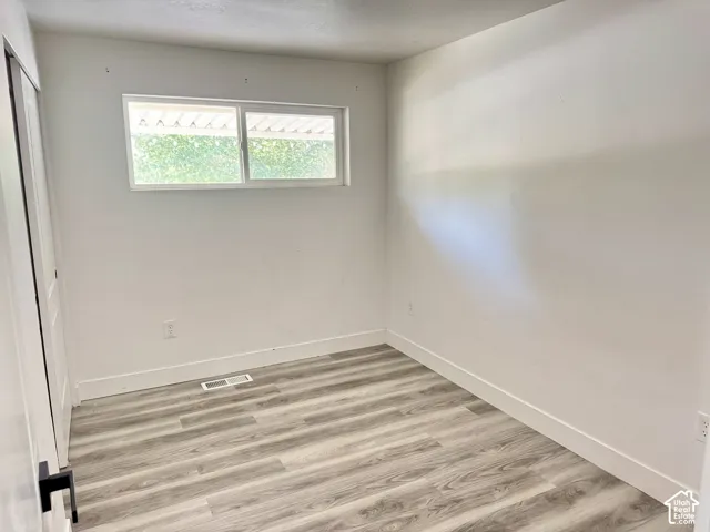 Wood-finish flooring, white walls, and a window with a garden backdrop