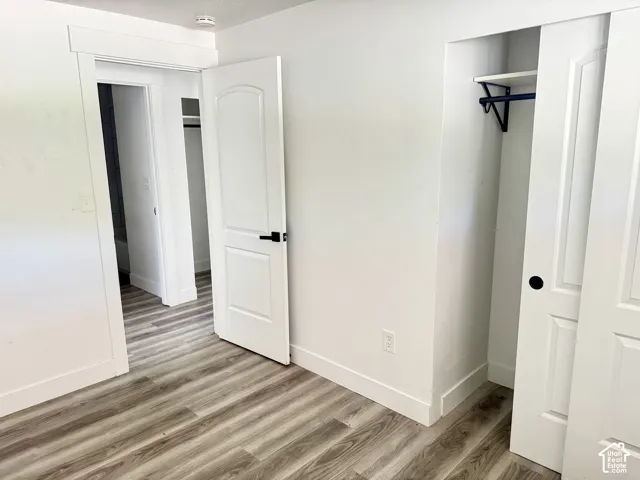 Wood-finish flooring throughout, bright white walls, and a built-in closet with sliding doors