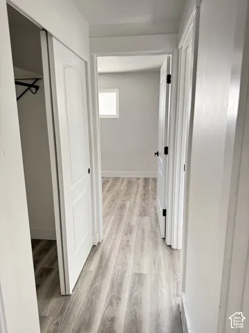 Hallway with wood-finish flooring, white walls, and white paneled doors