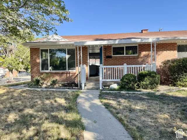 Brick exterior with a covered porch, white railing, and a concrete pathway