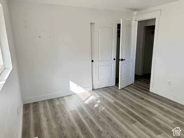 Wood-finish flooring, white walls, white trim, and white doors with black hardware