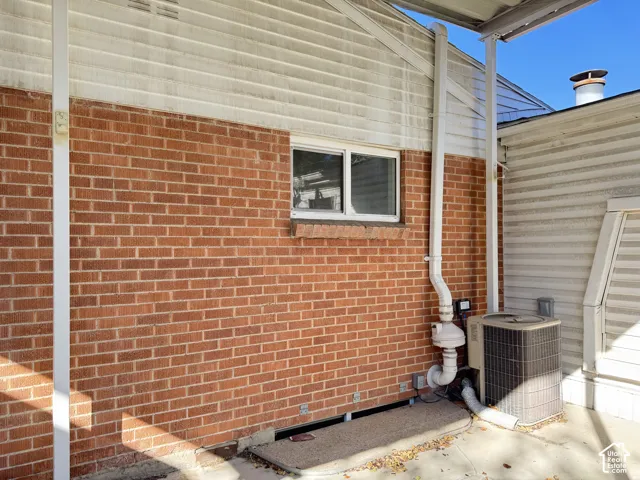 Brick exterior wall with white siding, white framed window, and an outdoor HVAC unit