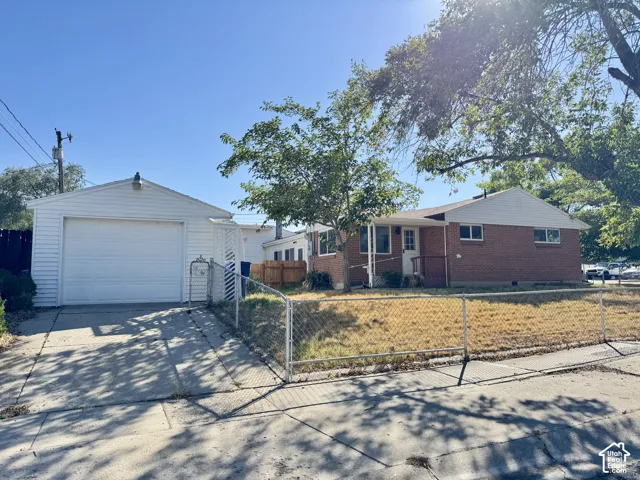 Brick exterior with white trim, a detached garage, and a chain-link fence