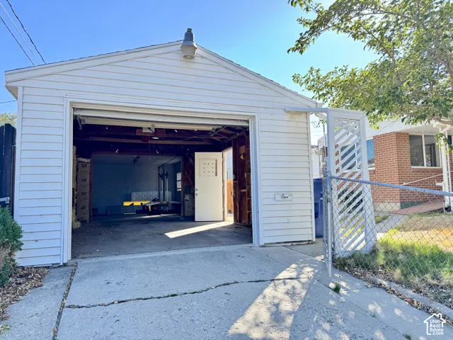 Detached garage with white vinyl siding, a pitched roof, and an overhead garage door
